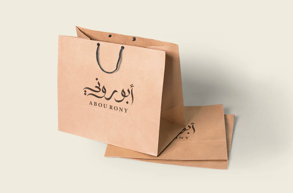 Concept mockup of the Abou Rony bilingual logo on kraft takeaway bags.
